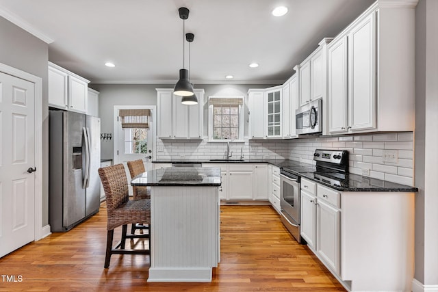 kitchen with a kitchen island, white cabinets, hanging light fixtures, and stainless steel appliances