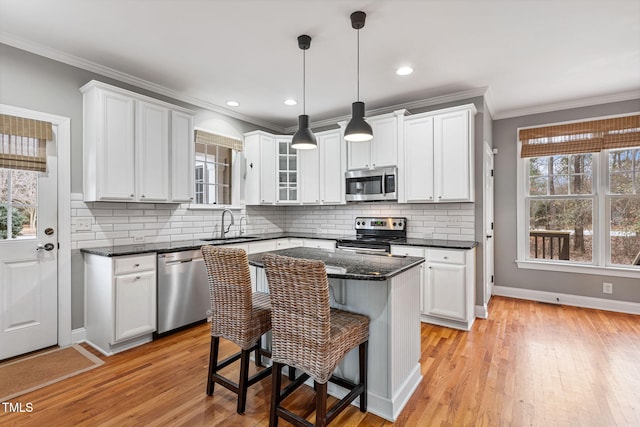 kitchen with pendant lighting, appliances with stainless steel finishes, white cabinets, a center island, and a breakfast bar area