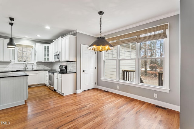 kitchen featuring appliances with stainless steel finishes, white cabinetry, sink, light hardwood / wood-style flooring, and pendant lighting