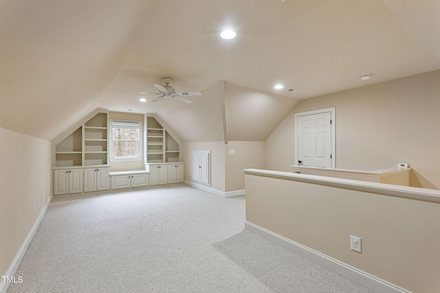 bonus room featuring built in shelves, ceiling fan, light carpet, and lofted ceiling