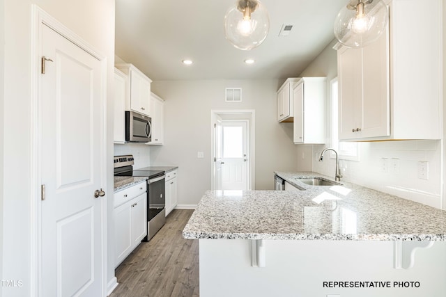 kitchen with stainless steel appliances, white cabinetry, sink, and a breakfast bar area