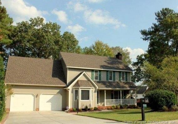 view of front facade featuring a porch, a garage, and a front lawn