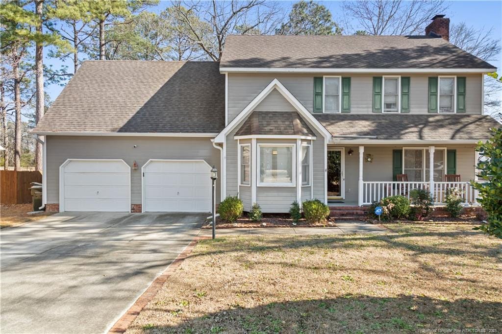 view of front of property featuring a front lawn, a porch, and a garage