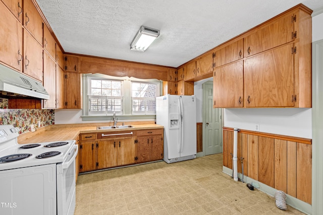 kitchen with sink, a textured ceiling, white appliances, and wood walls