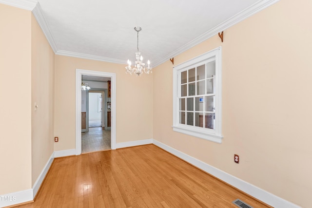 spare room with hardwood / wood-style flooring, ornamental molding, and a chandelier