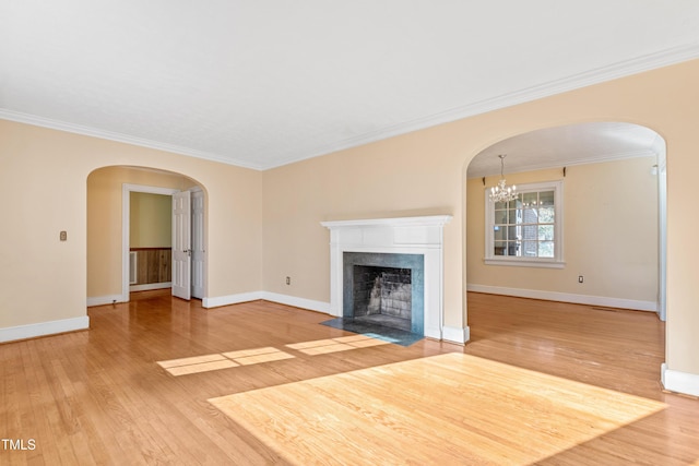 unfurnished living room with crown molding, an inviting chandelier, a premium fireplace, and hardwood / wood-style floors