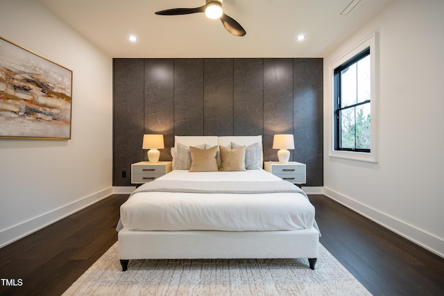 bedroom featuring ceiling fan, wood walls, and dark hardwood / wood-style flooring