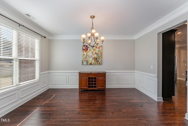 unfurnished dining area with dark hardwood / wood-style flooring, an inviting chandelier, and crown molding