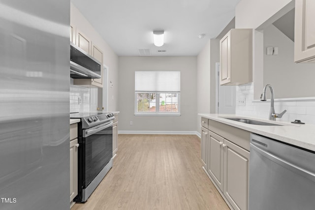 kitchen with exhaust hood, stainless steel appliances, light wood-type flooring, sink, and backsplash