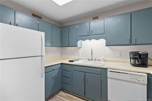 kitchen with sink, blue cabinets, white appliances, and light hardwood / wood-style flooring