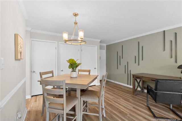 dining area with light hardwood / wood-style flooring, an inviting chandelier, and ornamental molding