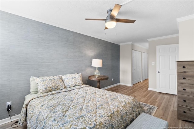 bedroom with ceiling fan, light hardwood / wood-style floors, crown molding, and a closet