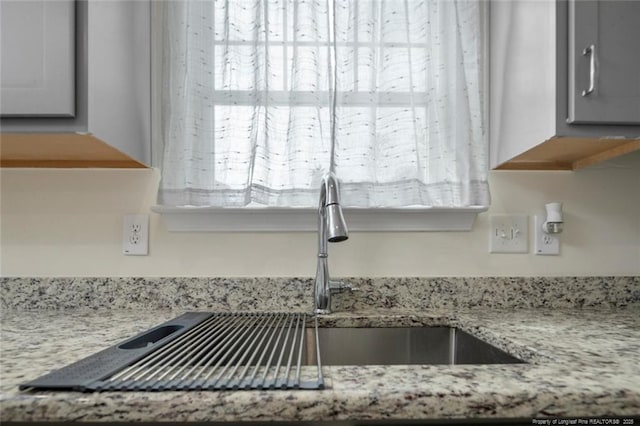 kitchen featuring light stone counters and sink