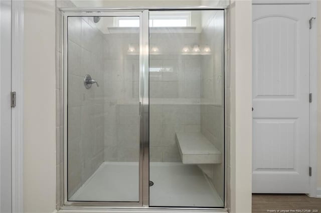 bathroom with wood-type flooring and a shower with shower door