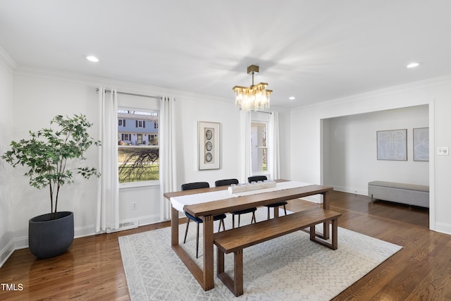 dining room with dark hardwood / wood-style floors, ornamental molding, and a notable chandelier