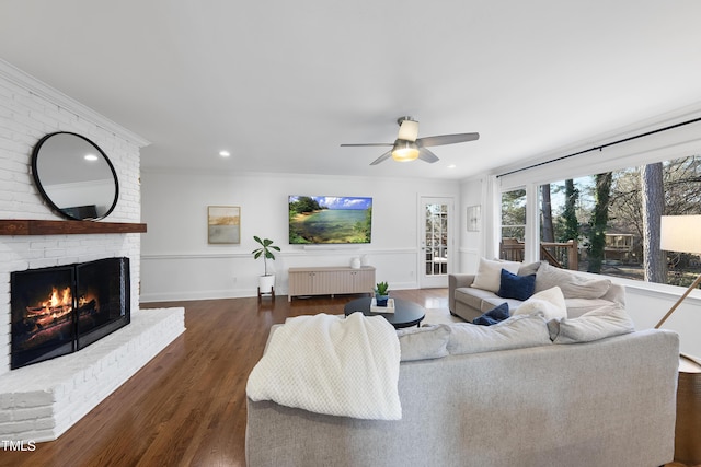 living room with ceiling fan, a brick fireplace, dark wood-type flooring, ornamental molding, and radiator heating unit