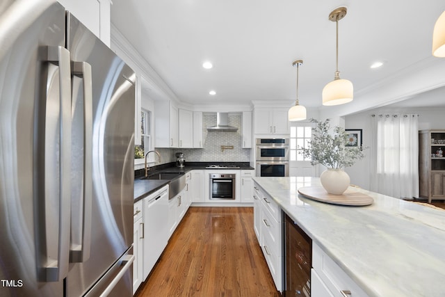 kitchen with appliances with stainless steel finishes, tasteful backsplash, dark stone counters, wall chimney range hood, and white cabinets