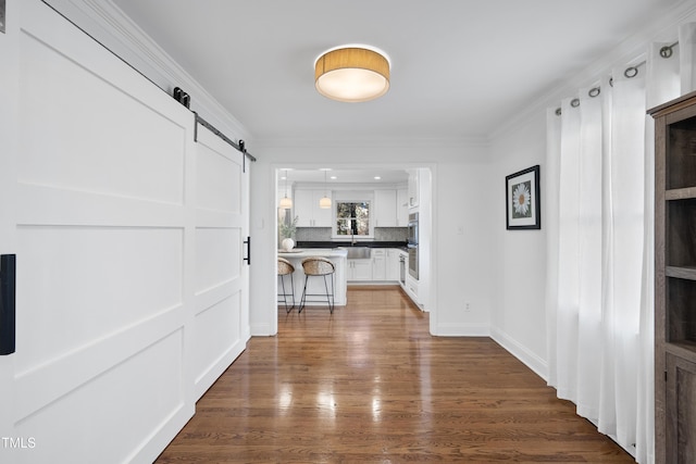 hall with ornamental molding, a barn door, hardwood / wood-style floors, and sink