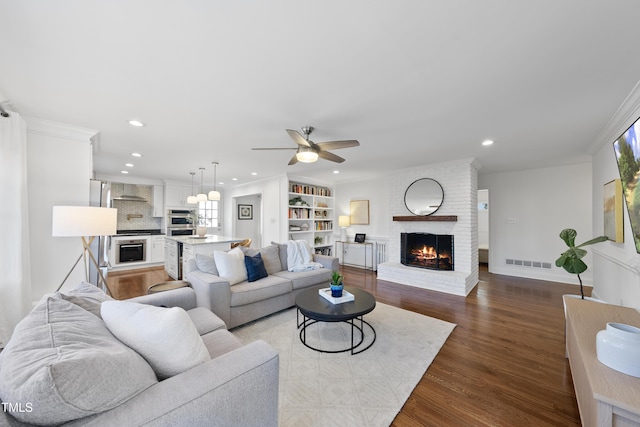 living room featuring ceiling fan, a fireplace, crown molding, and light hardwood / wood-style floors