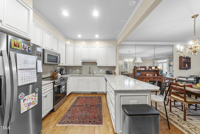 kitchen with appliances with stainless steel finishes, pendant lighting, white cabinets, a chandelier, and light stone countertops