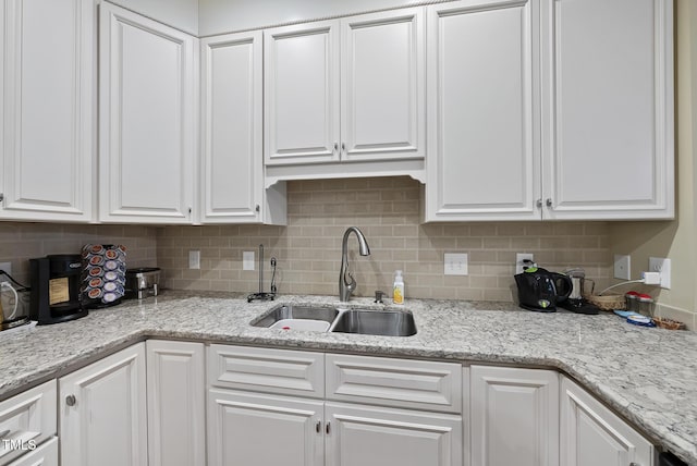 kitchen with tasteful backsplash, sink, light stone counters, and white cabinets