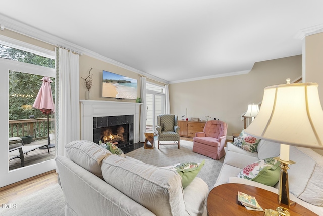 living room featuring crown molding, plenty of natural light, a fireplace, and light wood-type flooring