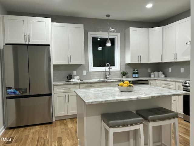 kitchen with white cabinetry, sink, light stone counters, appliances with stainless steel finishes, and light wood-type flooring