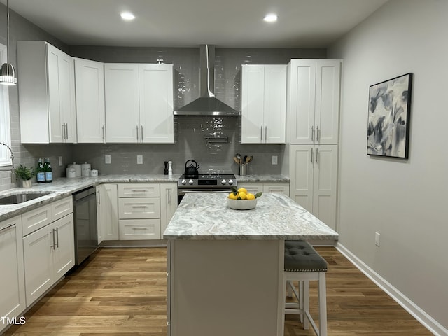 kitchen featuring wall chimney exhaust hood, white cabinetry, and appliances with stainless steel finishes