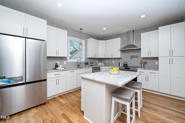 kitchen featuring wall chimney exhaust hood, stainless steel appliances, and white cabinetry