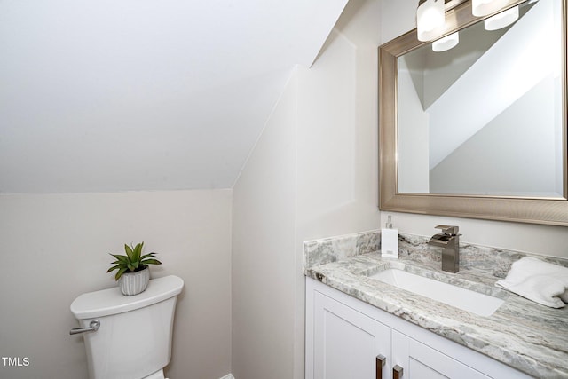 bathroom with lofted ceiling, vanity, and toilet