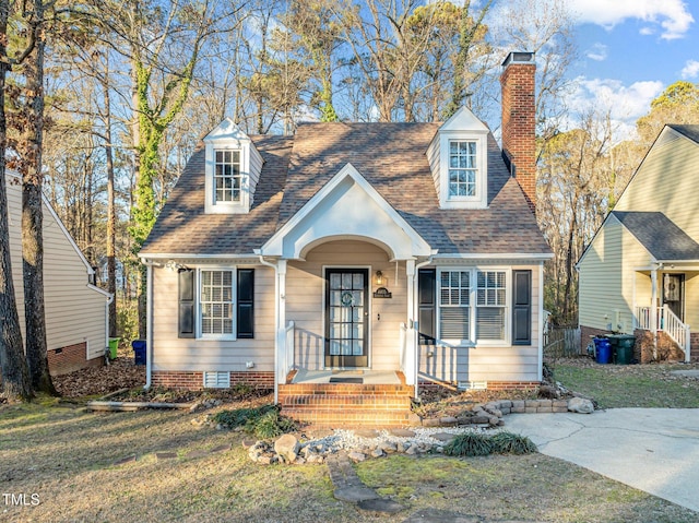 cape cod home featuring a front lawn