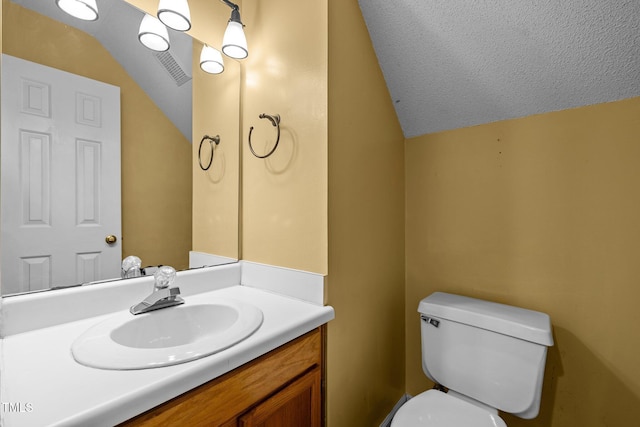 bathroom with vaulted ceiling, toilet, a textured ceiling, and vanity