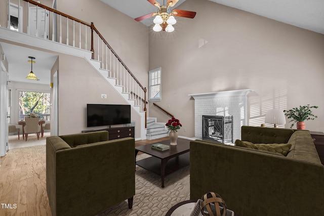 living room featuring ceiling fan, a high ceiling, and light hardwood / wood-style flooring