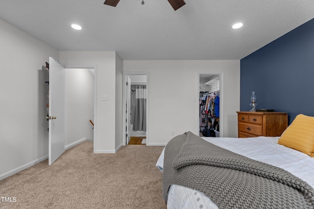 carpeted bedroom with a walk in closet, ceiling fan, and a closet