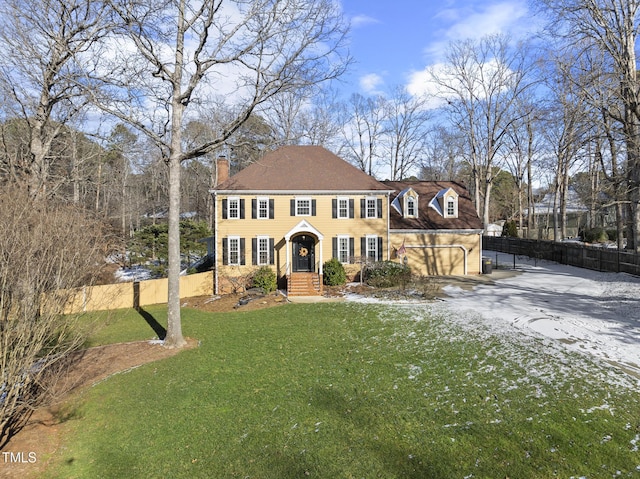 colonial house featuring a garage and a front lawn