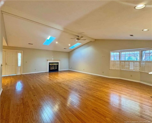 unfurnished living room featuring light hardwood / wood-style flooring, lofted ceiling with skylight, and ceiling fan