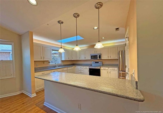 kitchen featuring white cabinetry, hanging light fixtures, stainless steel appliances, light hardwood / wood-style flooring, and kitchen peninsula