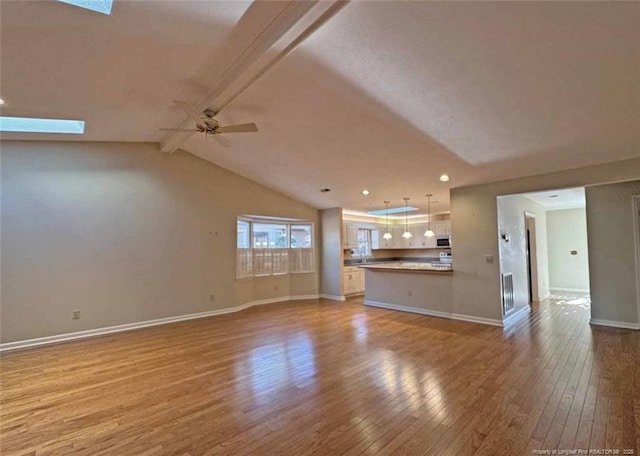 unfurnished living room featuring vaulted ceiling with beams, ceiling fan, and light wood-type flooring