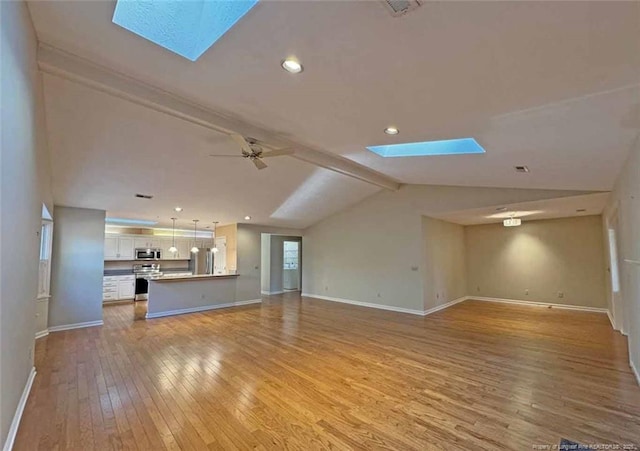 unfurnished living room with vaulted ceiling with skylight, ceiling fan, and light wood-type flooring