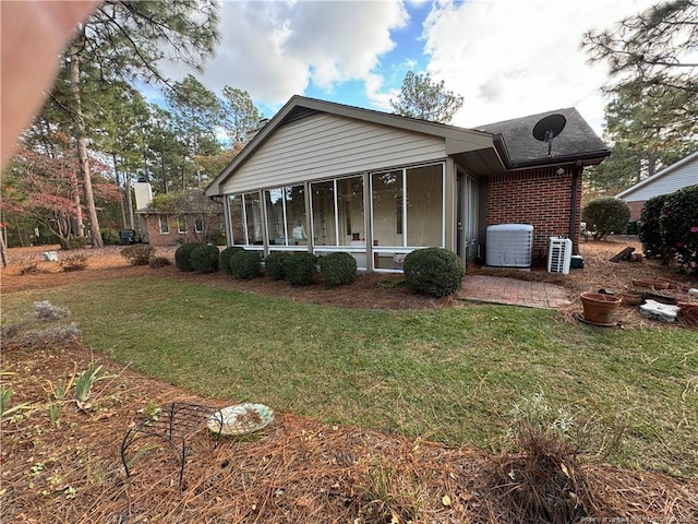 view of front facade featuring a front yard, central AC, and a sunroom