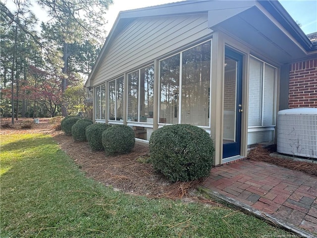 view of side of home with central air condition unit, a sunroom, and a yard