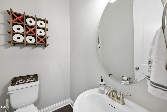 half bath featuring a sink, baseboards, and toilet