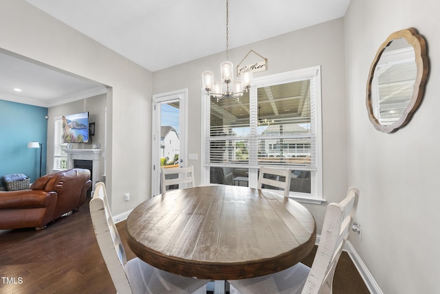 dining area featuring an inviting chandelier, baseboards, wood finished floors, and a fireplace