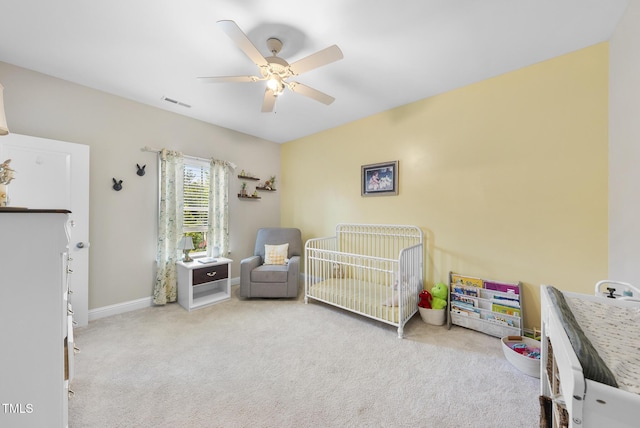 carpeted bedroom featuring visible vents, a ceiling fan, baseboards, and a nursery area