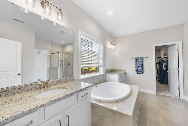 bathroom featuring visible vents, a bath, two vanities, a shower stall, and a sink