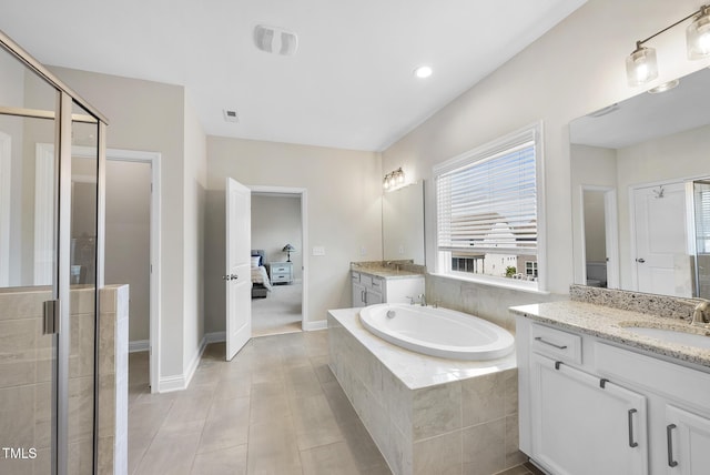 ensuite bathroom featuring a sink, a bath, a healthy amount of sunlight, and two vanities