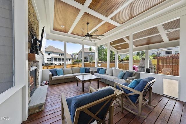 sunroom featuring a ceiling fan, coffered ceiling, and an outdoor living space with a fireplace