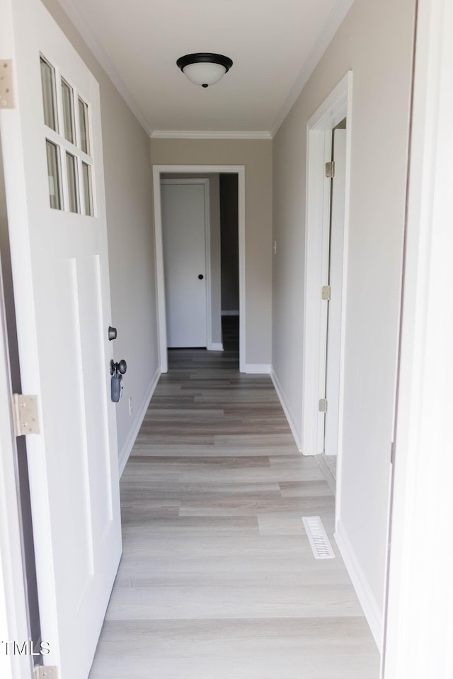 hall with light wood-type flooring and crown molding