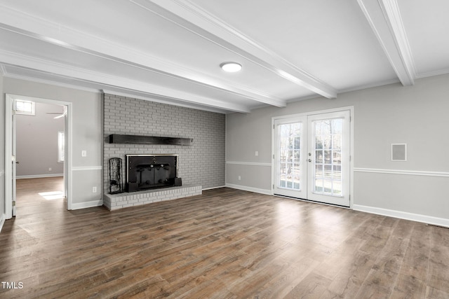 unfurnished living room featuring french doors, hardwood / wood-style flooring, ornamental molding, a fireplace, and beamed ceiling