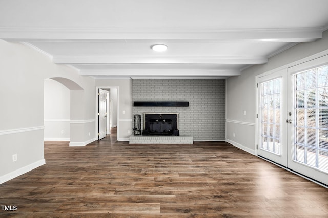 unfurnished living room with beamed ceiling, dark wood-type flooring, and a brick fireplace